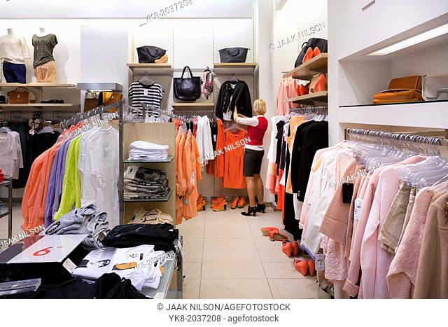 Woman, buyer in fashion shop aisle. Retail outlet and fashion shop interior. Shopping