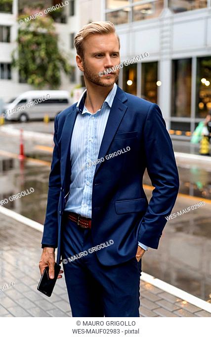 Young businessman with smartphone during a rainy day in Bangkok