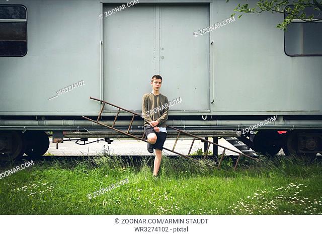 young man leaning against an old rail car
