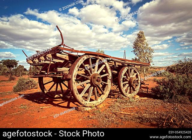 Australia – Outback savanna with an old vintage derelict horse-drawn carriage at the bush under cloudy sky