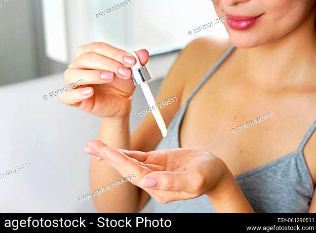 Beautiful woman holding a pipette in her hand with serum moisturizing anti aging antioxidant. Focus on hand