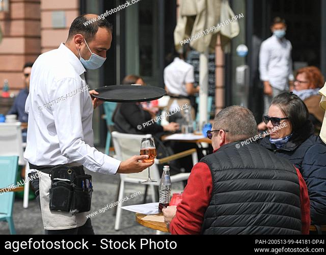 13 May 2020, Rhineland-Palatinate, Mainz: Aris Astanoglou (l) serves Manuela and Thomas Los from Nidderau (Hesse) with mouthguards in the outdoor area of the...