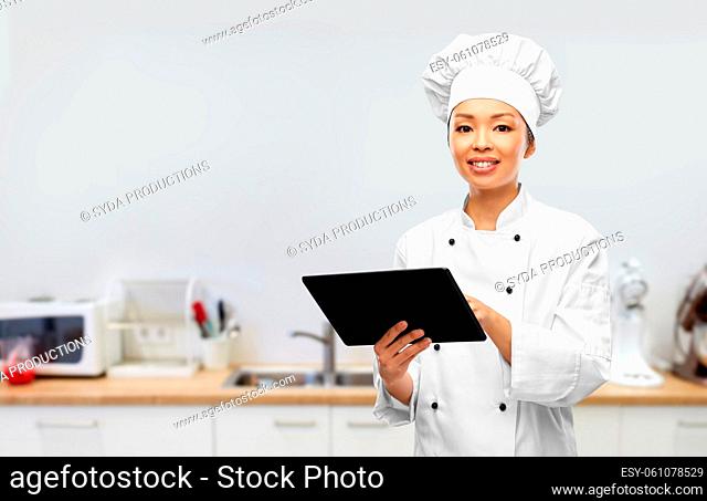 smiling female chef with tablet pc in kitchen