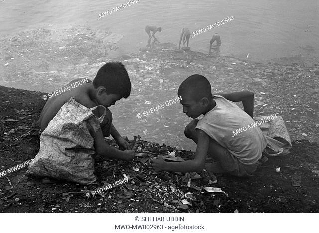 Waste from the small factories are regularly dumped on the banks of the river Buriganga polluting the waters Young boys grab this waste