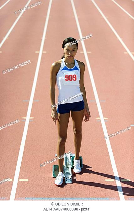 Female runner standing at starting line, portrait