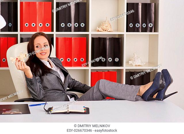 Businesswoman with a model of plane sits on a workplace in the office