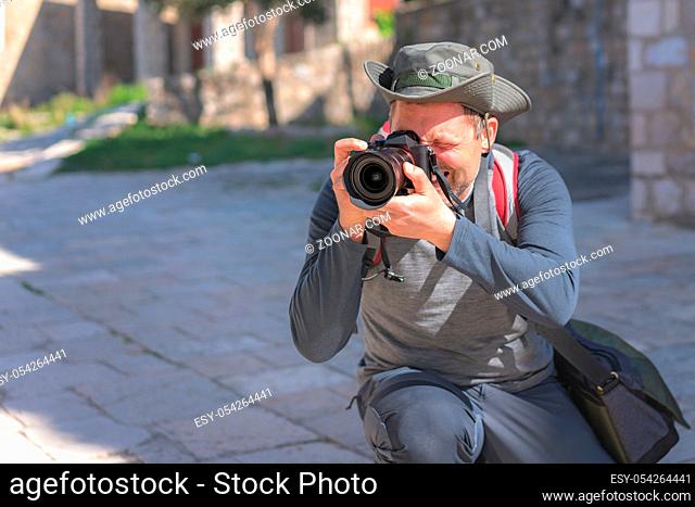 Portrait of a professional street and travel photographer with a camera pointed toward the subject