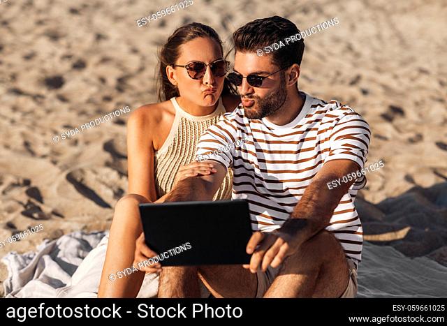 happy couple with tablet pc at on summer beach