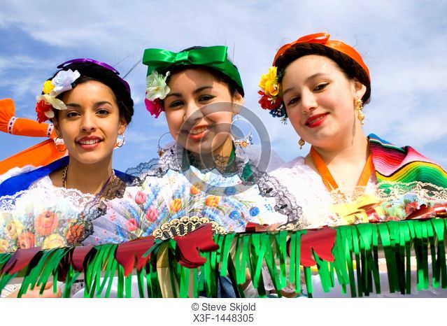 Hispanic teen girls dressed in traditional Mexican holiday attire holding fans  Cinco de Mayo Fiesta St Paul Minnesota USA