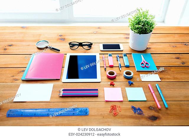 education, school supplies, art, creativity and object concept - close up of stationery and tablet pc computer with smartphone on wooden table