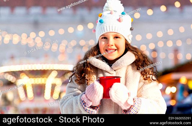 little girl with cup of tea over christmas market