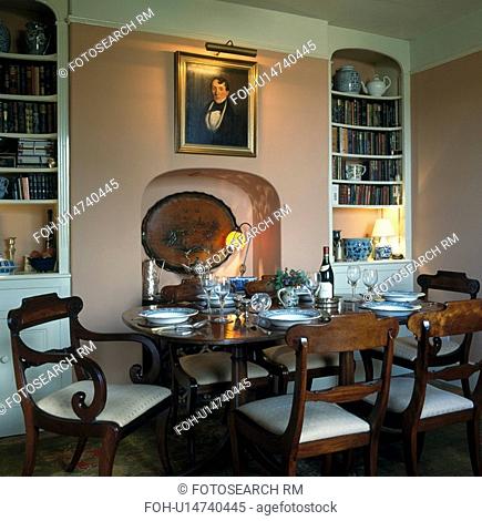 Alcove bookshelves in dining room with antique furniture and picture above fireplace alcove