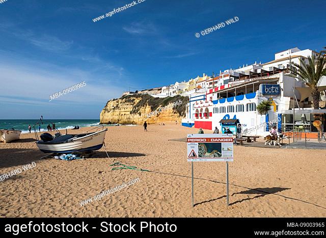 On the beach of Carvoeiro, a sign warns of rockfall caused by coastal erosion, Algarve, Faro district, Portugal