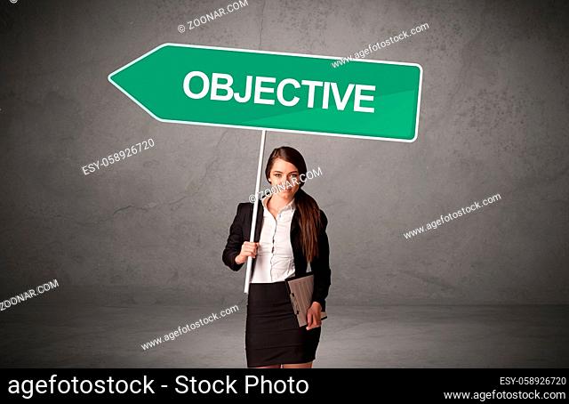 Young business person in casual holding road sign with OBJECTIVE inscription, new business direction concept