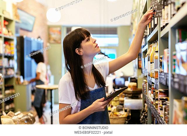 Woman with tablet at shelf in a store