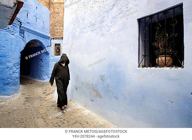 Man dressed traditionally walking in a street in the Chefchaouen Old Town Medina, Morocco