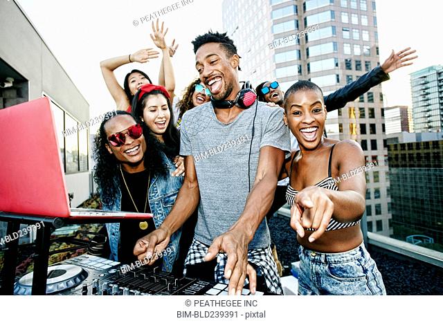 Friends posing with DJ on urban rooftop