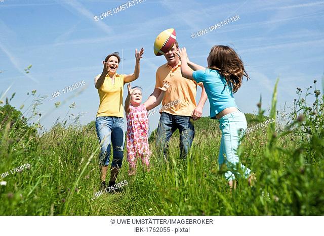 Family playing joyfully with a ball in a flower meadow