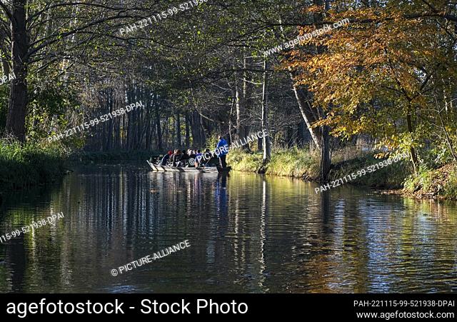 PRODUCTION - 12 November 2022, Brandenburg, Burg: In sunny weather, a barge sails on a river through the autumnal landscape in the Spreewald