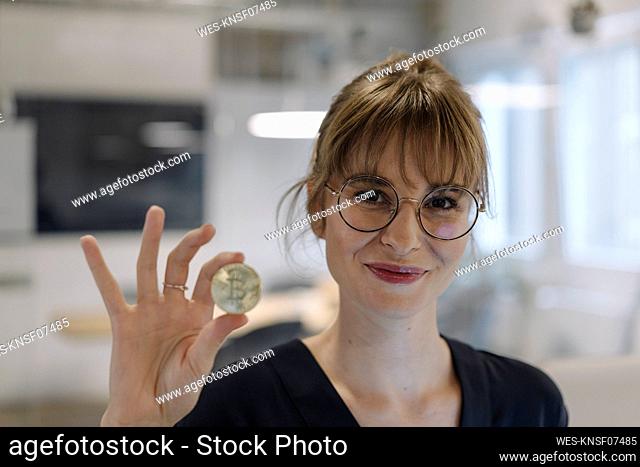 Portrait of businesswoman holding bitcoin in office