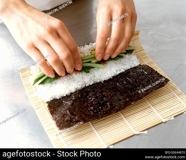 Making Maki Sushi: Hands Rolling Vegetable and Rice Filled Nori