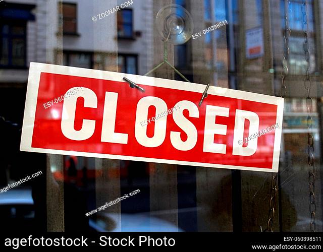 Closed sign a in shop window with blurred background reflections