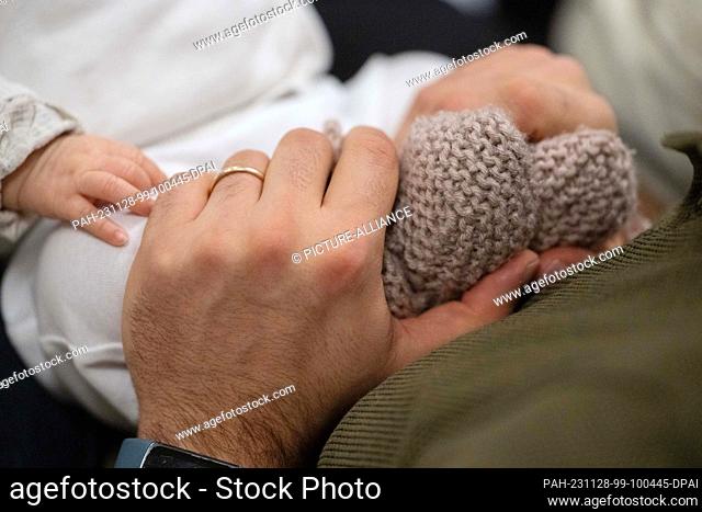 SYMBOL - 24 November 2023, Baden-Württemberg, Stuttgart: A father holds his child's feet during an infant handling course