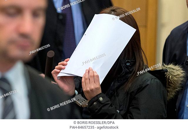 A defendant arrives in a courtroom while covering her face with a folder in Frankfurt am Main, Germany, 10 October 2016. Five South Korean nations are charged...