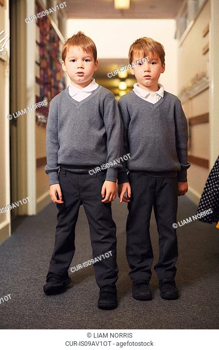 Portrait of elementary schoolboy twins in school corridor