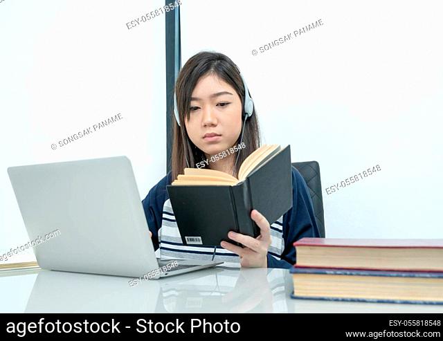 Young female student sitting in living room and learning online using laptop at desk .E-learning