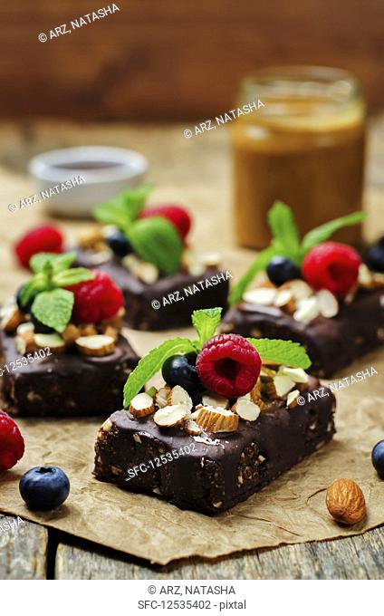 Raw vegan no bake chocolate, dates and almond brownies with chocolate frosting and berries