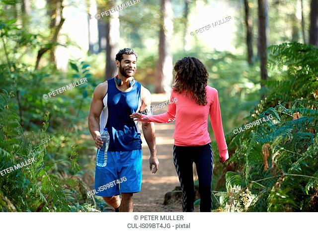Male and female runners sharing bottled water in forest