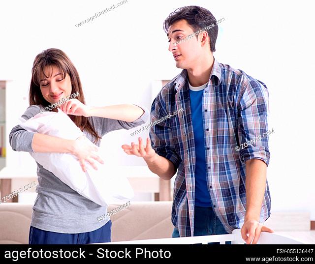 The young parents with their newborn baby near bed cot