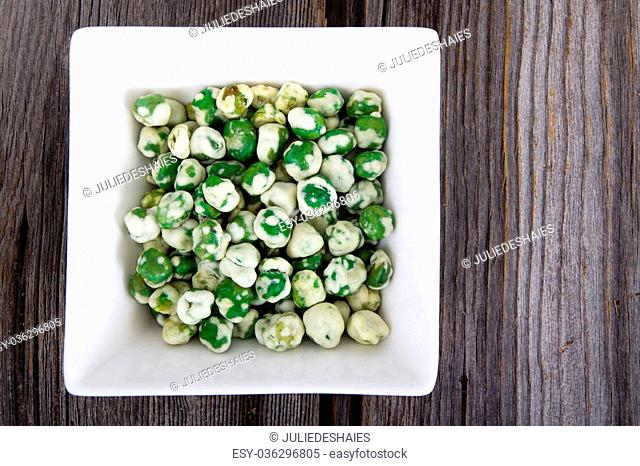 Wasabi coated peas on a square bowl over wood table