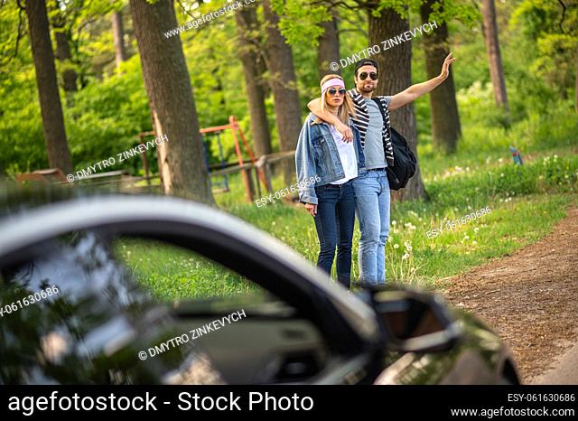 Adventure. Two people trying to stop the car in the forest and looking joyful