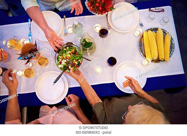 Group of people sitting at table, about to serve food, overhead view