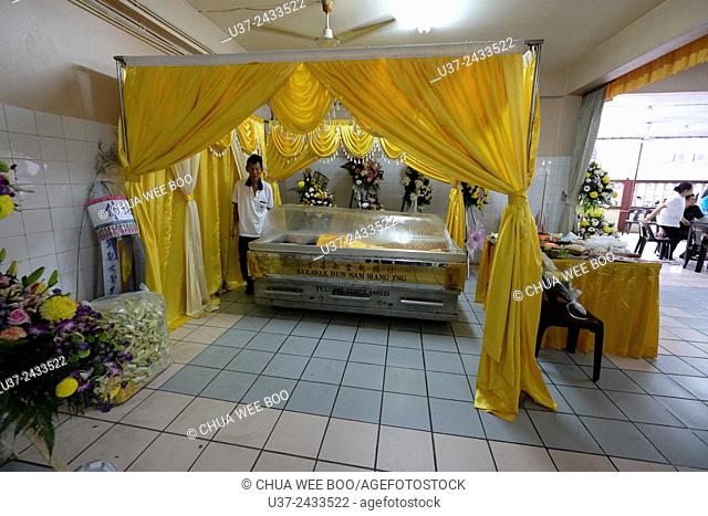 The deceased in a cold glass-panel casket before transferring to a wooden coffin. Sarawakian chinese funeral ceremony. Malaysia