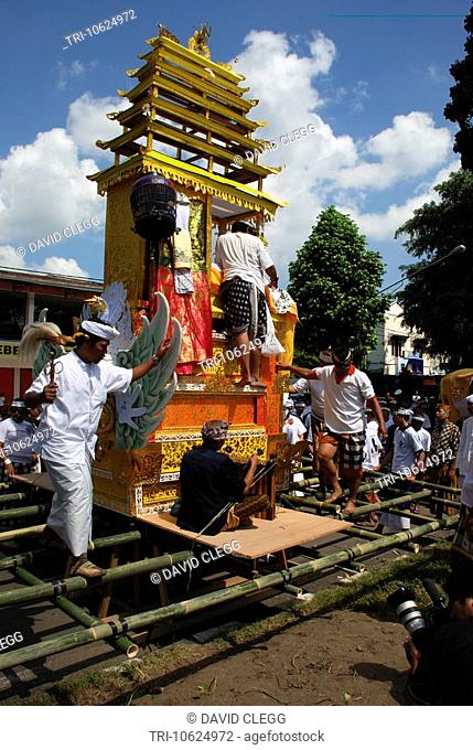 Man adjusting the coffin on the tall gold and orange funeral bier on main road in Balinese Hindu cremation ceremony Cakranegara Lombok Barat NTB Indonesia