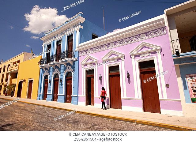 Woman walking in front of the colorful colonial buildings in the city center, Merida, Yucatan Province, Mexico, Central America