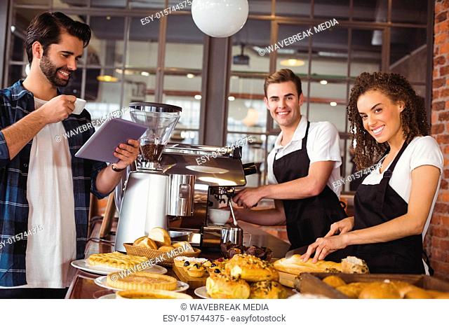 Smiling colleagues serving customer with tablet and coffee