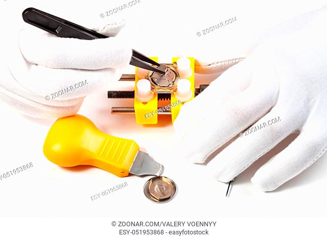 watchmaker workshop - removing battery from quartz watch by tweezers on white background