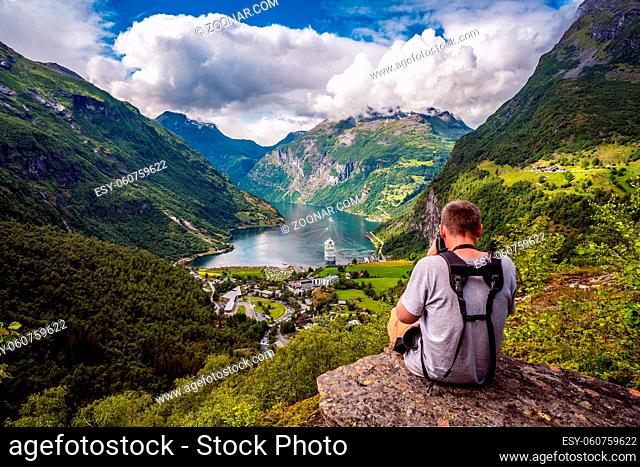 Geiranger Fjord Beautiful Nature Norway, a UNESCO World Heritage Site. Nature photographer tourist with camera shoots. The fjord is one of Norway's most visited...