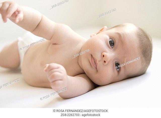 Baby boy spinning around over a white bed sheet with an extended arm, Madrid, Spain