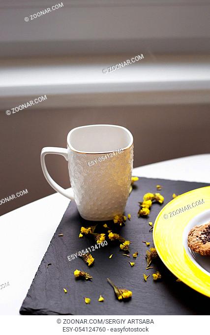 Oatmeal cookies with chocolate on bright yellow plate and cup of coffee