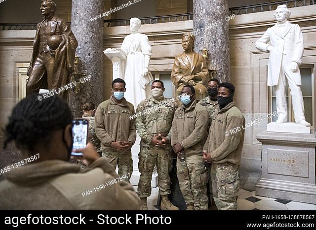 Members of the National Guard take photos next to the statue of Rosa Parks in Statuary Hall of the U.S. Capitol, as the House of Representatives vote on H
