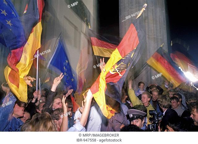 European and German flags, citizens of Berlin celebrating the reunion of East and West Germany in front of the Brandenburger Tor at night, DDR, October 3rd 1990