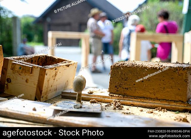 20 August 2023, Bavaria, Hallerstein: A freshly stamped adobe brick and tools lie on a table. Nearly 60 regional and almost forgotten crafts are presented at...