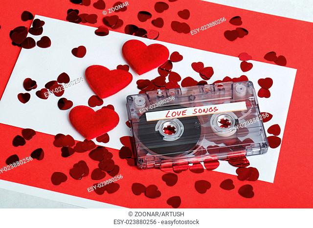 Audio cassette tape on red background with fabric heart