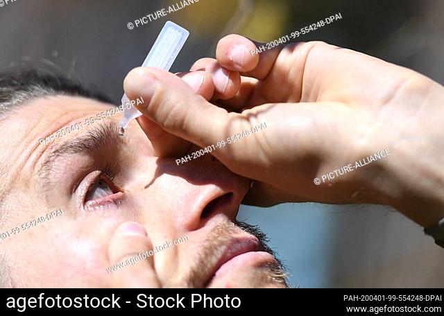 01 April 2020, Bavaria, Garmisch-Partenkirchen: ILLUSTRATION - A man with hay fever drips eye drops into his eyes. Photo: Angelika Warmuth/dpa