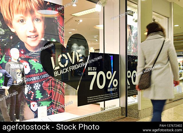 Topic picture BLACK FRIDAY on November 26th, 2020. A young woman with face mask, mask walks past the window of a fashion store
